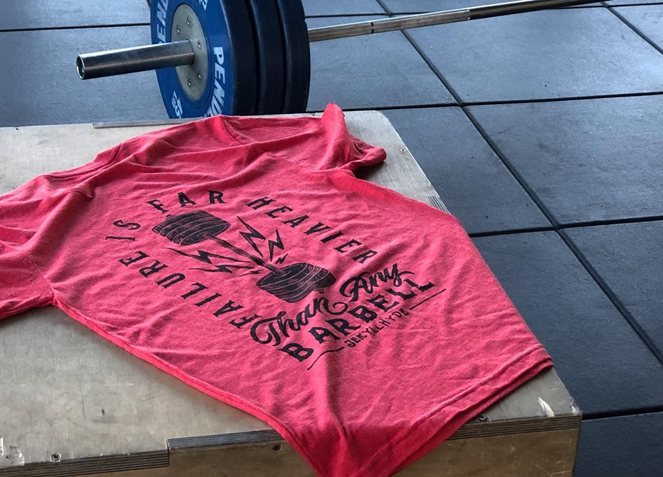 Red shirt on a plyo box with black screen print. 
