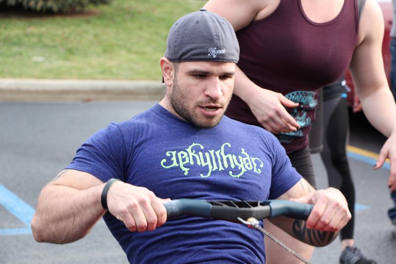 Man rowing with a blue tshirt with bright green Jekyllhyde logo on the front. 