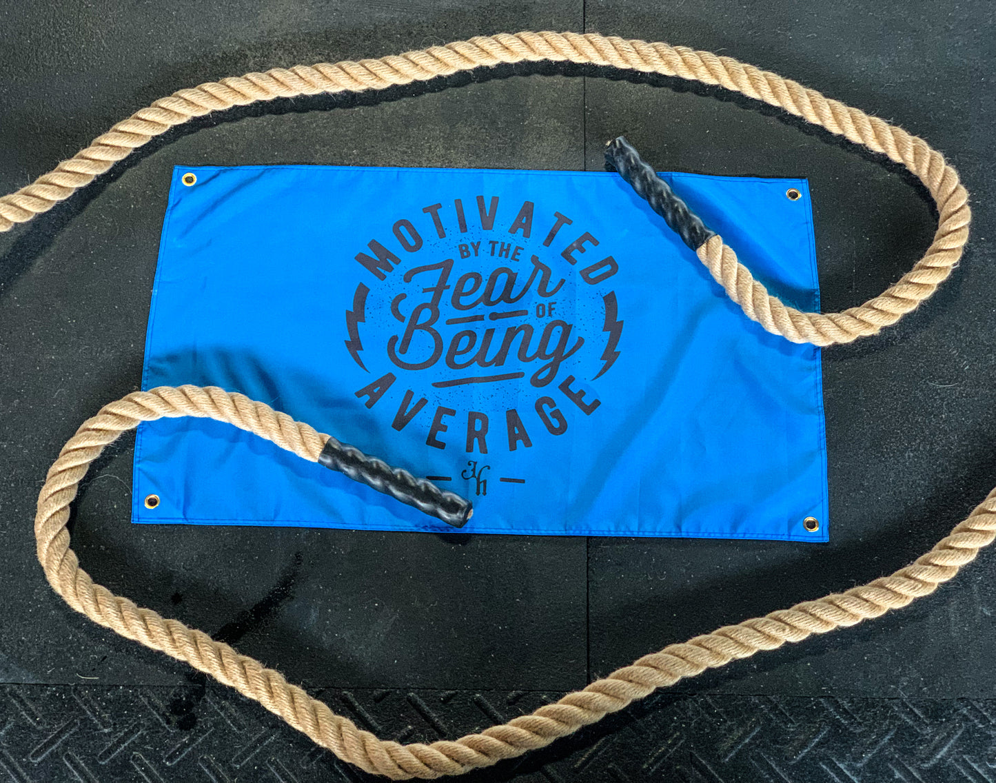 A blue gym flag laying on the ground with battle ropes over it. 