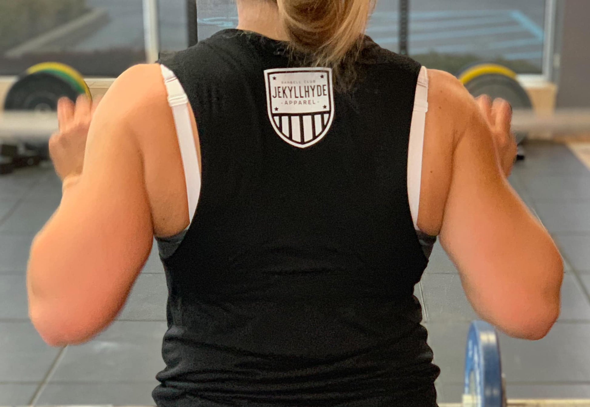 The back of a black muscle tee with a small shield in the neck area. 