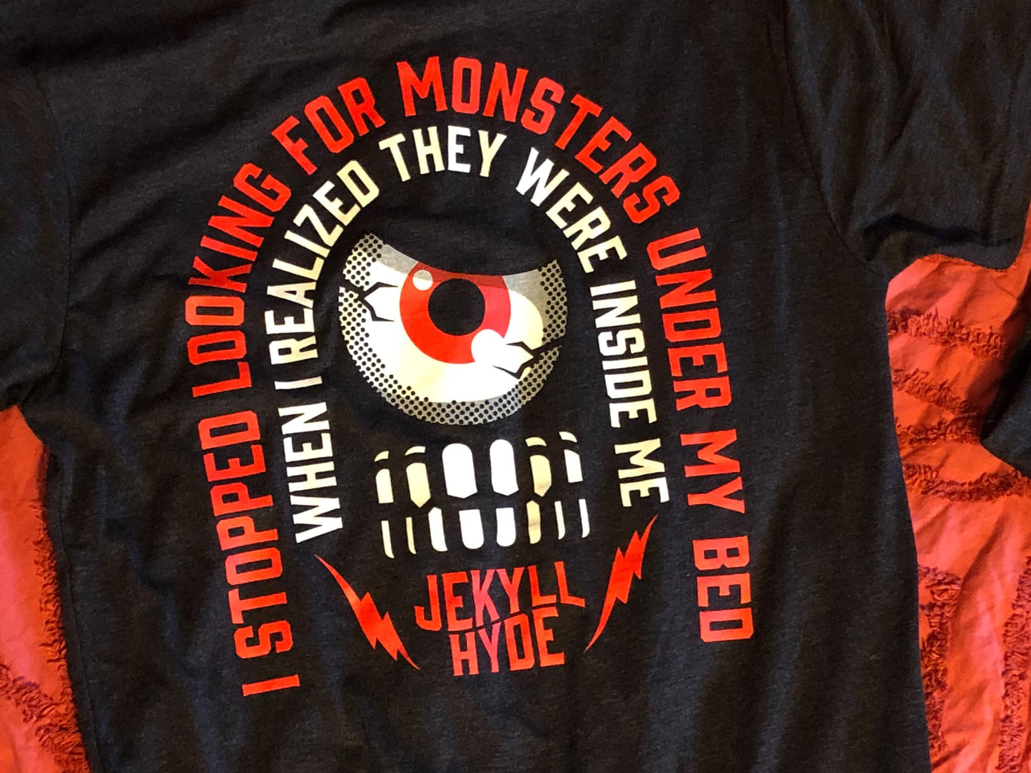 Black tshirt on a red background with text in a curved pattern. 