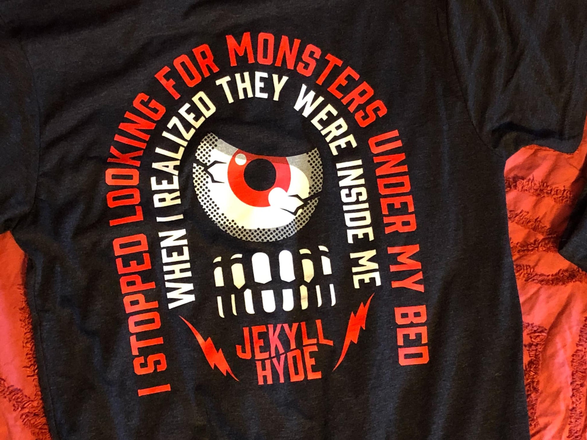 Black tshirt on a red background with text in a curved pattern. 