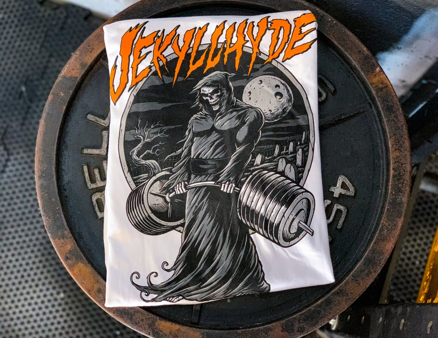 White shirt on a rusted weight with a deadlifting grim reaper. 