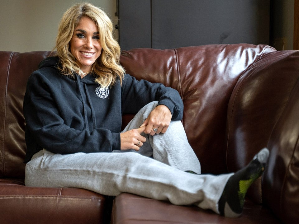Woman sitting on a couch in grey sweatpants. 