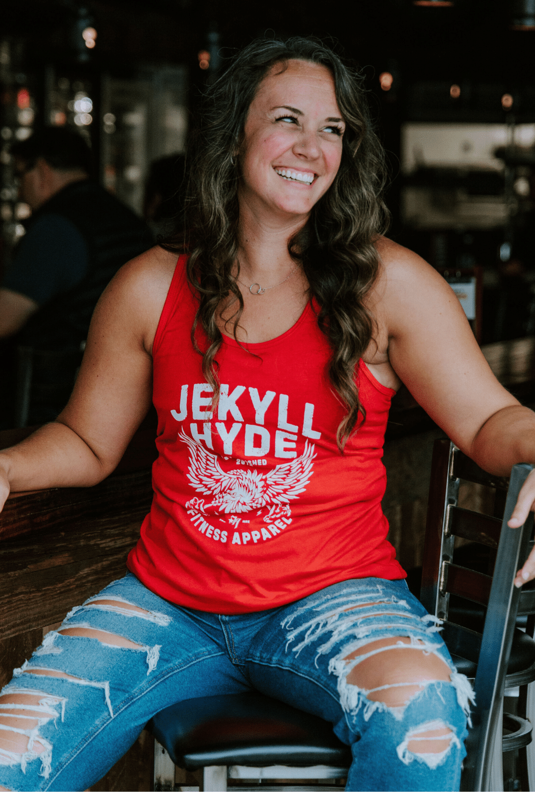 Woman sitting at a bar wearing a red tank with an eagle on it. 