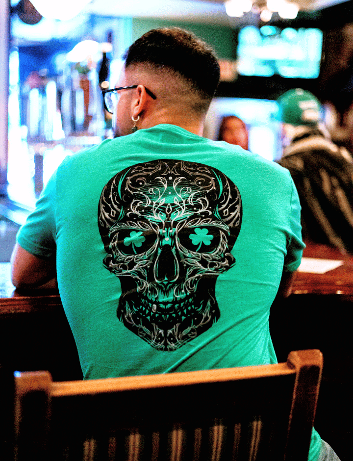 Man sitting at a bar in green sugar skull tshirt. 
