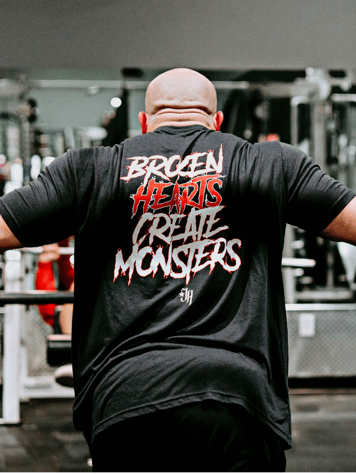 A muscular man exercising in a tshirt that reads "Broken hearts create monsters". 