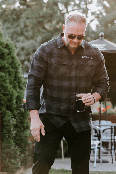 Man in Black flannel holding a beer. 