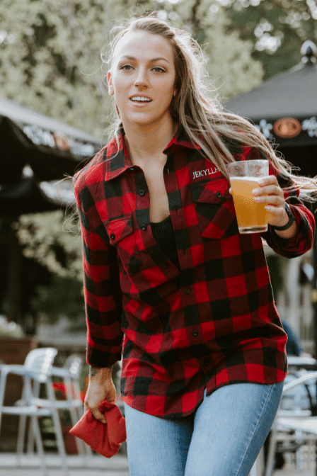Woman in red flannel throwing a bean bag. 
