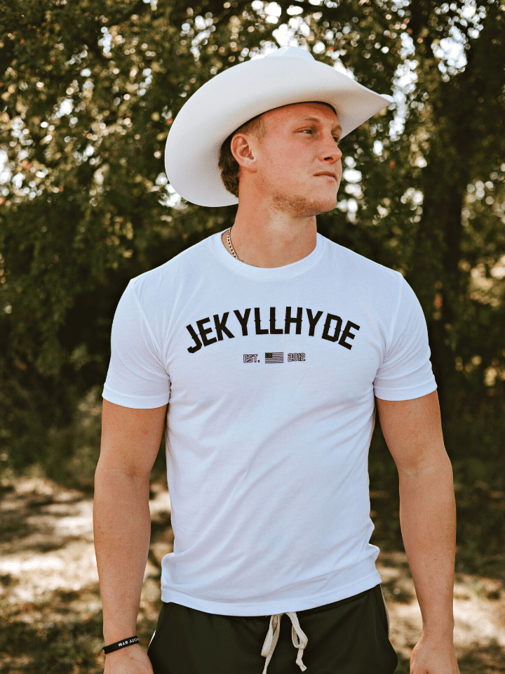 Guy in a white shirt and cowboy hat looking to the side. 