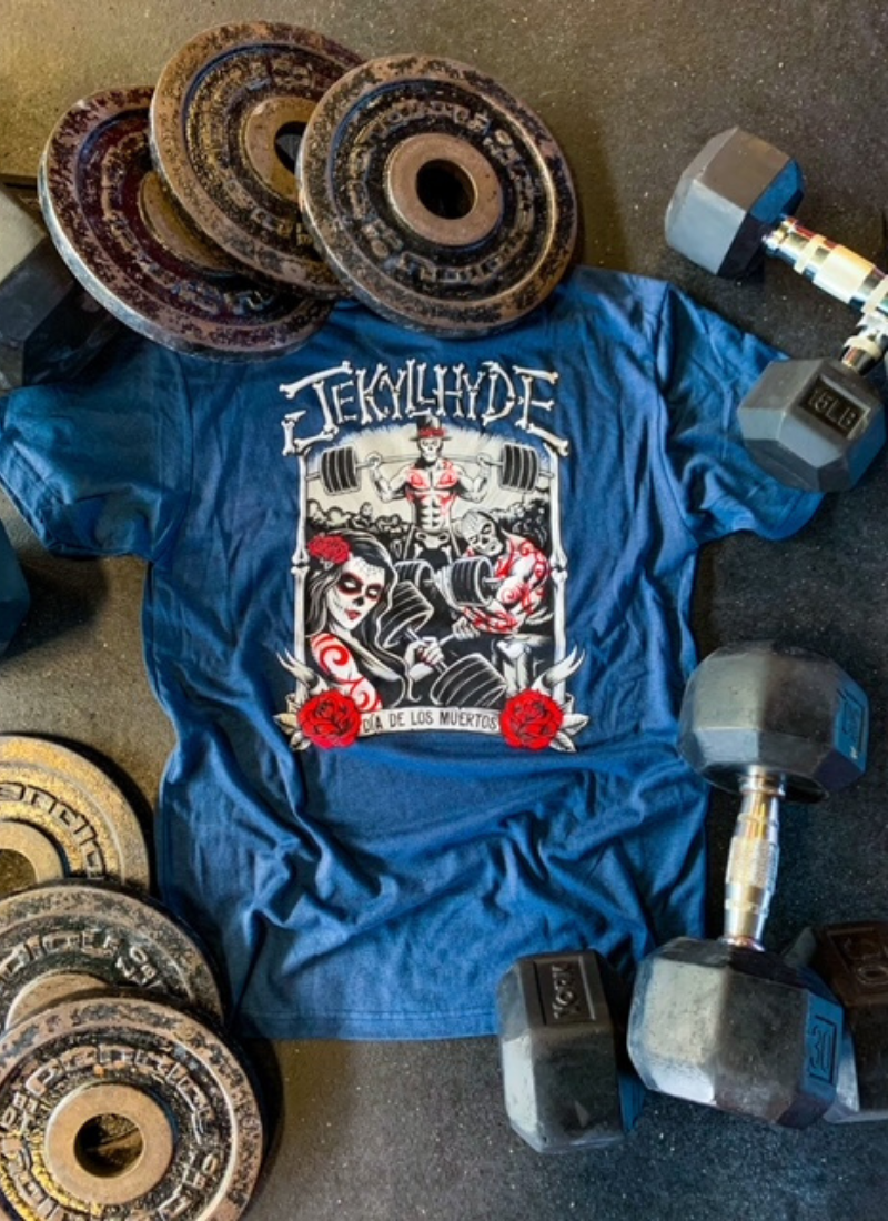 Flat lay of navy shirt depicting a gym scene with sugar skull people. 