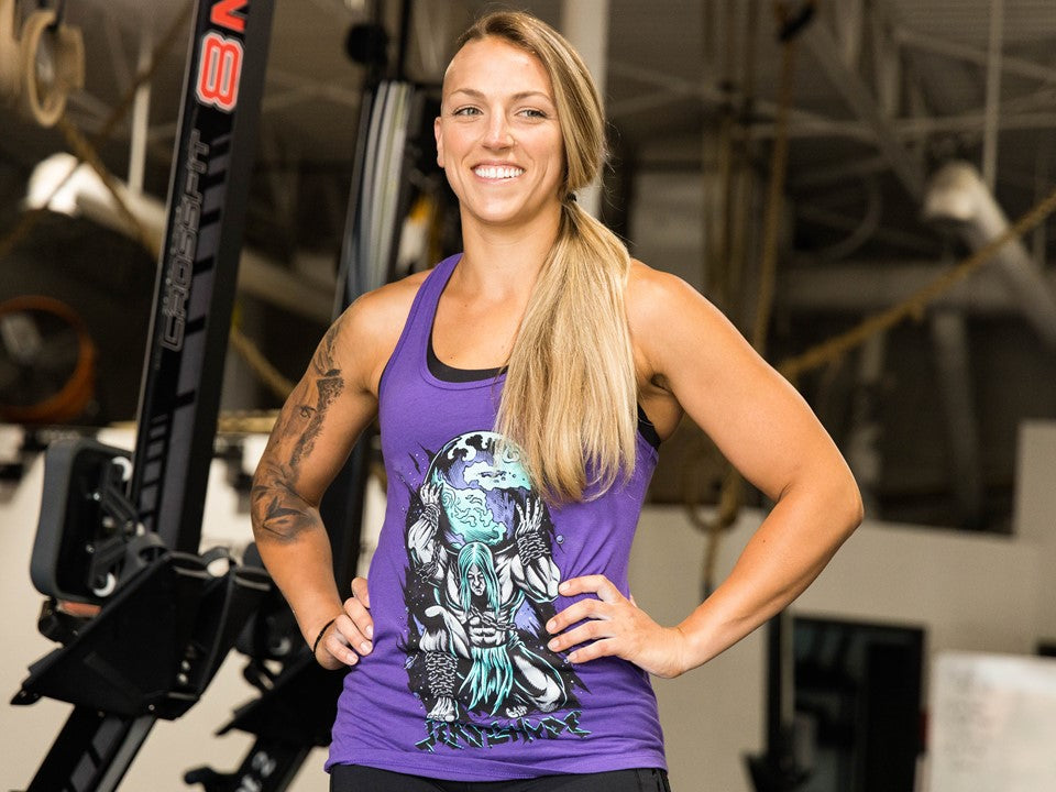 A fit woman looking to the side in a purple tank top. 