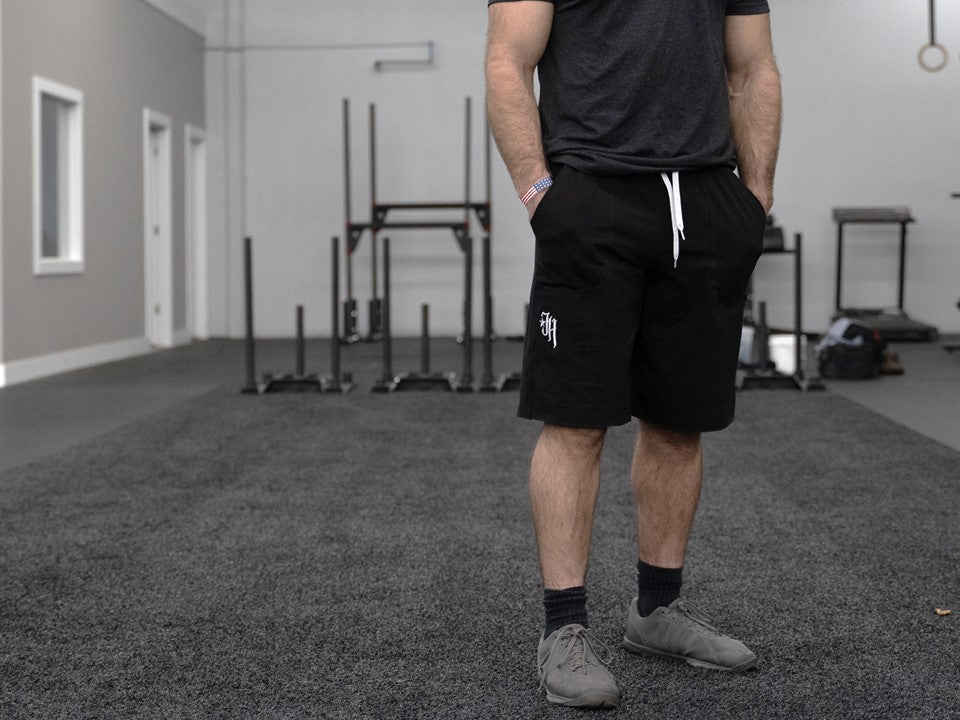 The bottom 3/4 of a muscular man standing on black turf. 