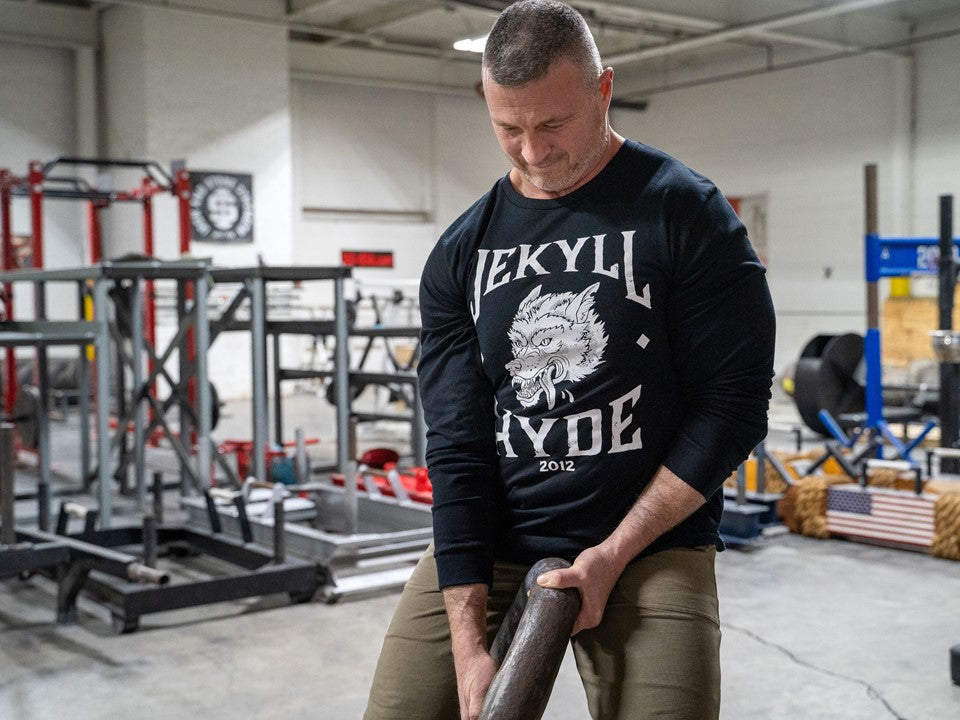 Man pulling a chain in a black long sleeve shirt with a wolf. 