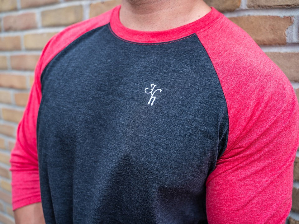 Close up of embroidered letters "JH" on a black and red raglan. 