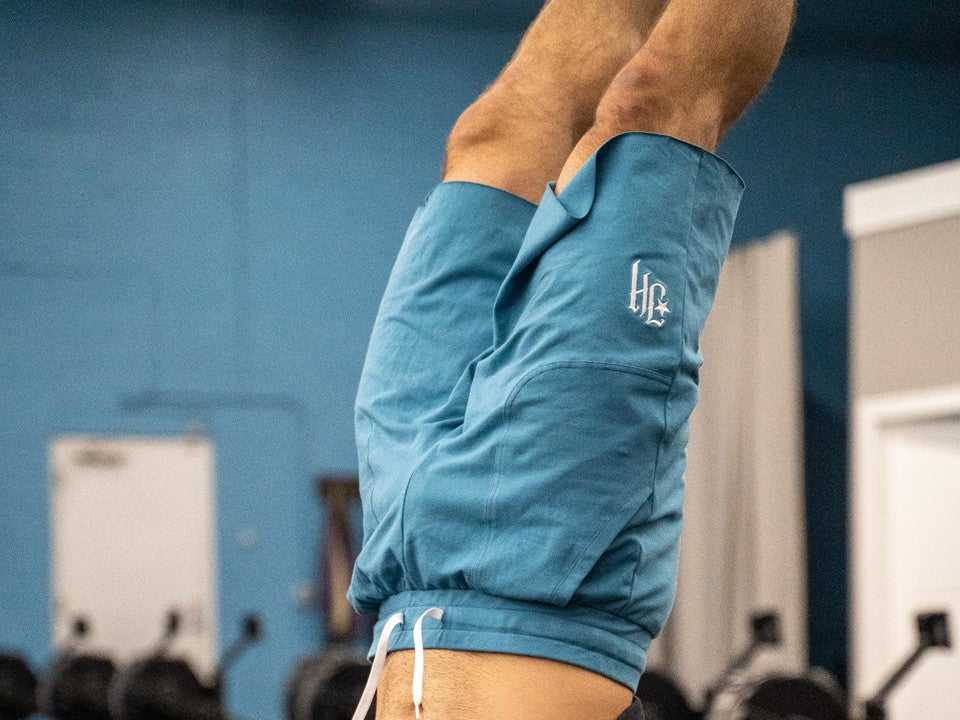 Blue shorts on  man doing a handstand. 