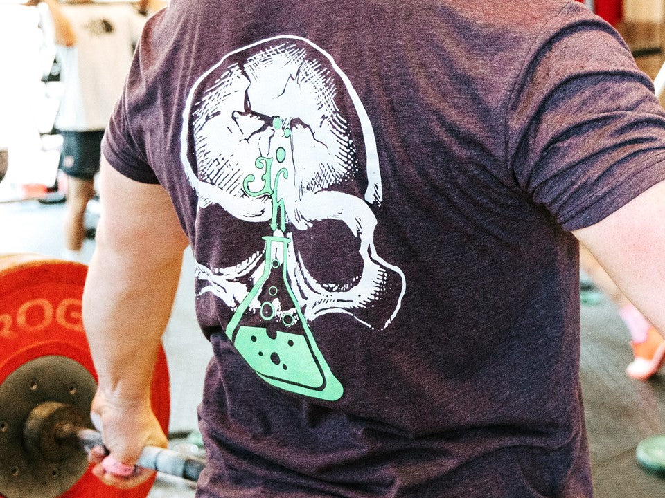 Close up of a purple shirt with a skull and beaker on it. 