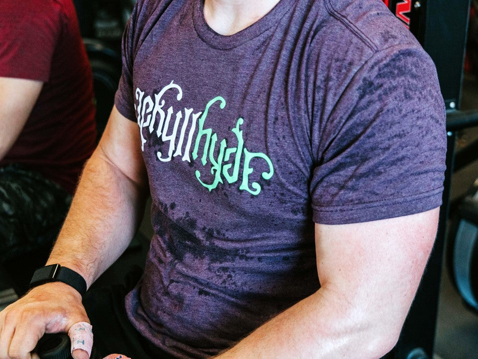 Close up of a man wearing a purple shirt with a jekyllhyde logo on the front. 