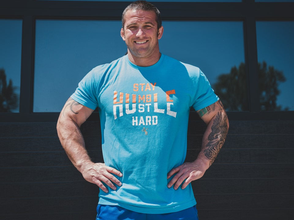 Muscular man with his hands on his hips wearing a blue shirt. 