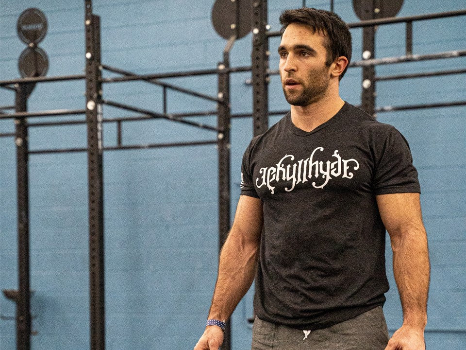 Man staring off into the distance at a gym while wearing a black Jekyllhyde tshirt. 