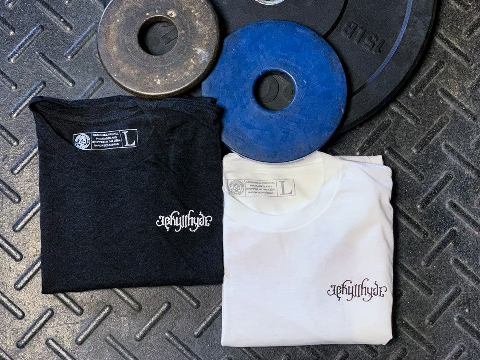 Black and white shirts folded on the ground with a Jekyllhyde logo on the left chest. 