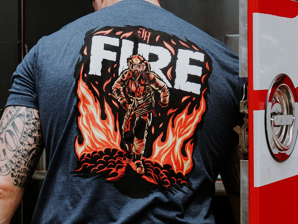 Close up of blue tshirt with a fireman running on the back. 