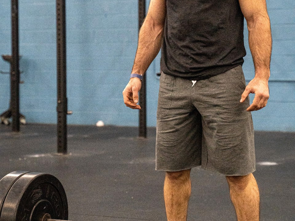A torso in grey shorts standing in a gym. 