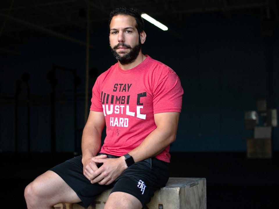 Man sitting on a box wearing a red shirt. 