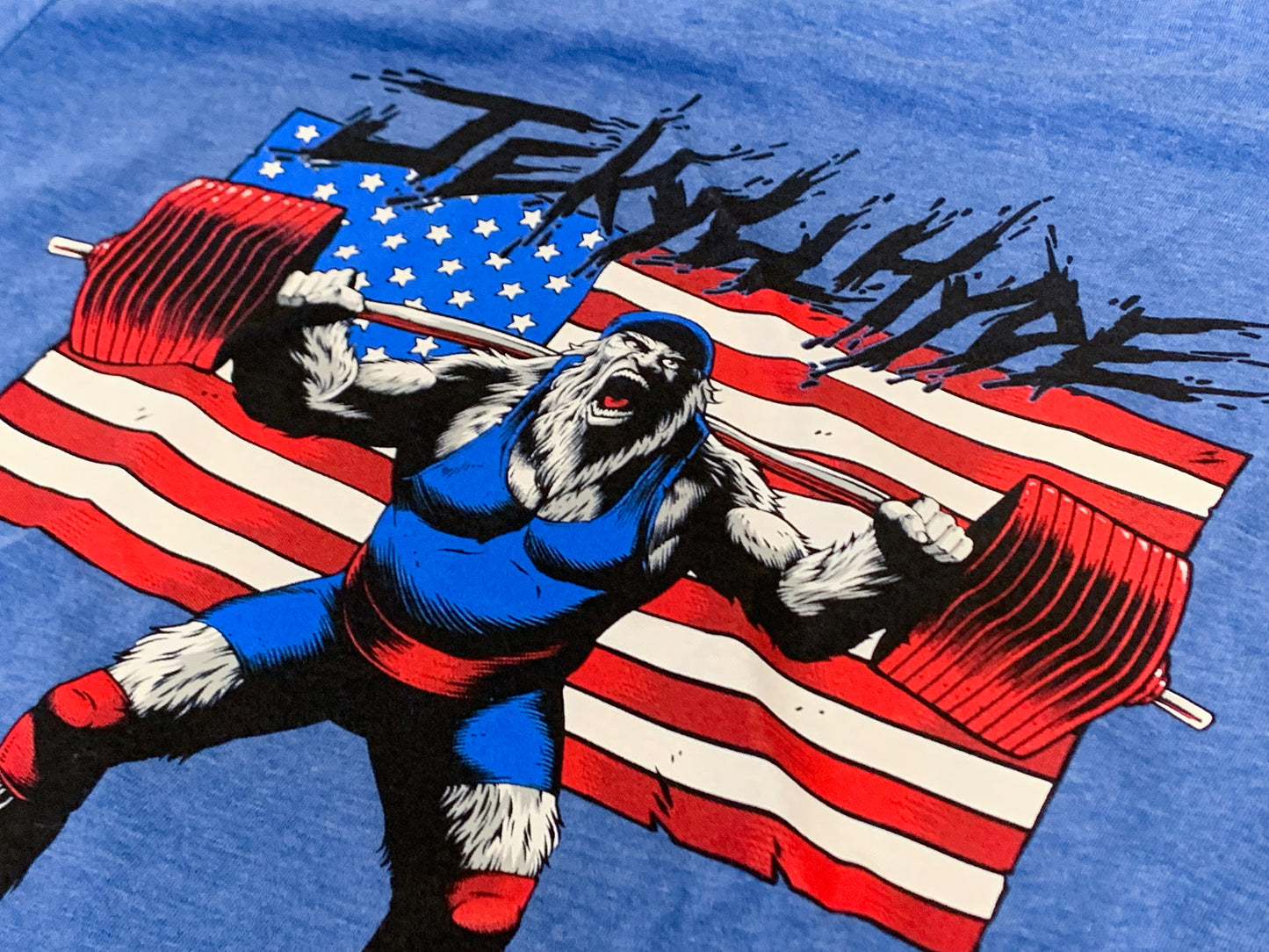 Print of a yeti squatting a heavy barbell with an american flag background. 