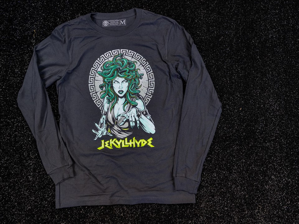A long sleeve shirt with medusa on the front laying on the floor. 