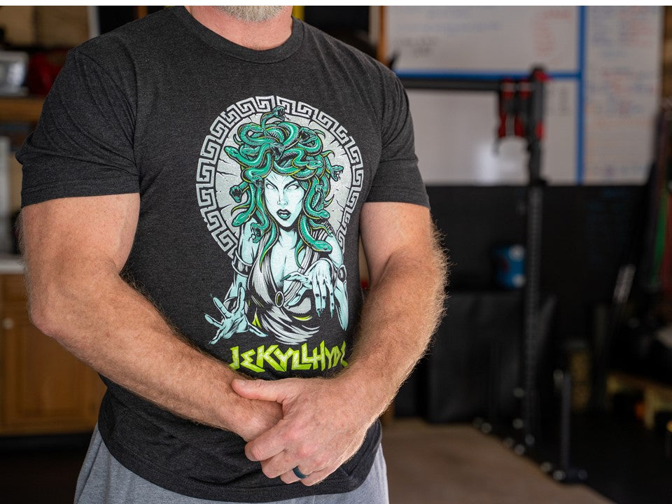 Man with his hands crossed in front of his body wearing a black t-shirt with Medusa on it. 