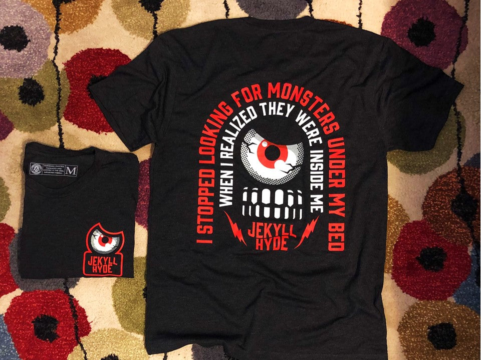 Black tshirt with an eyeball and teeth on a colorful rug. 