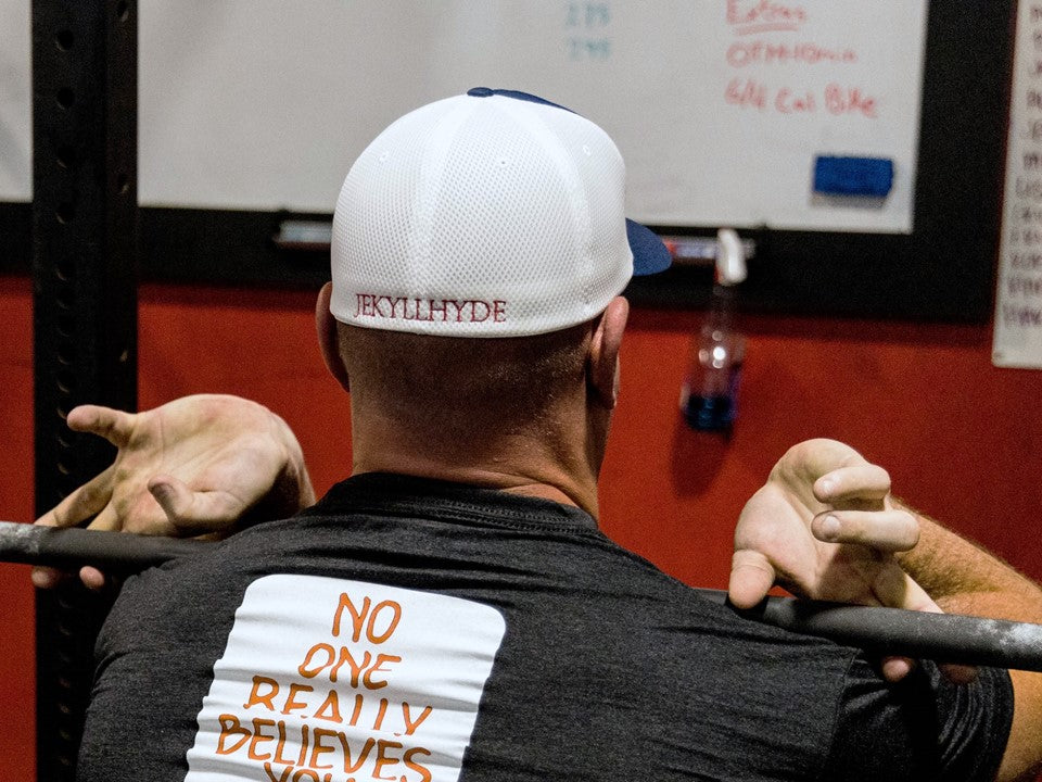 Man front squatting with a red, white and blue Jekyllhyde hat. 