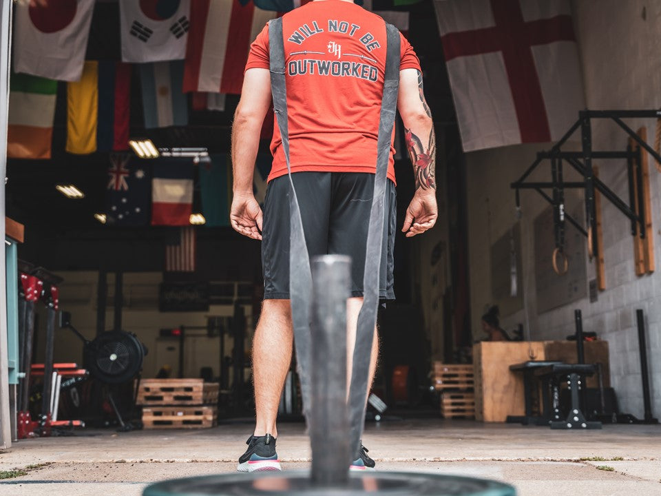 Man dragging a sled into a gym. 