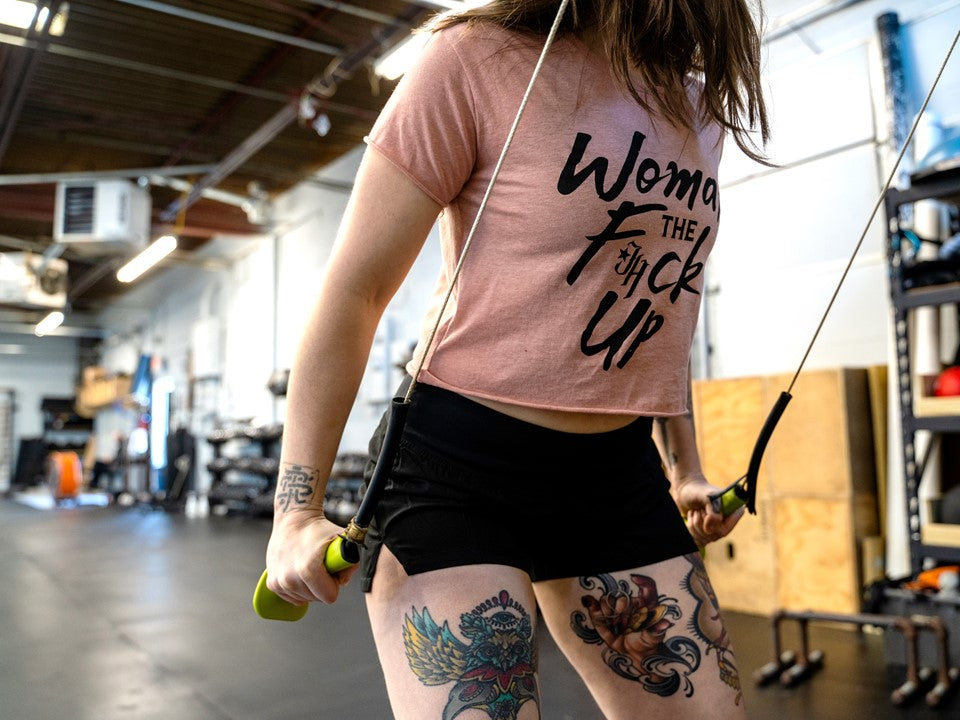 A woman in a pink crop using a ski erg machine. 