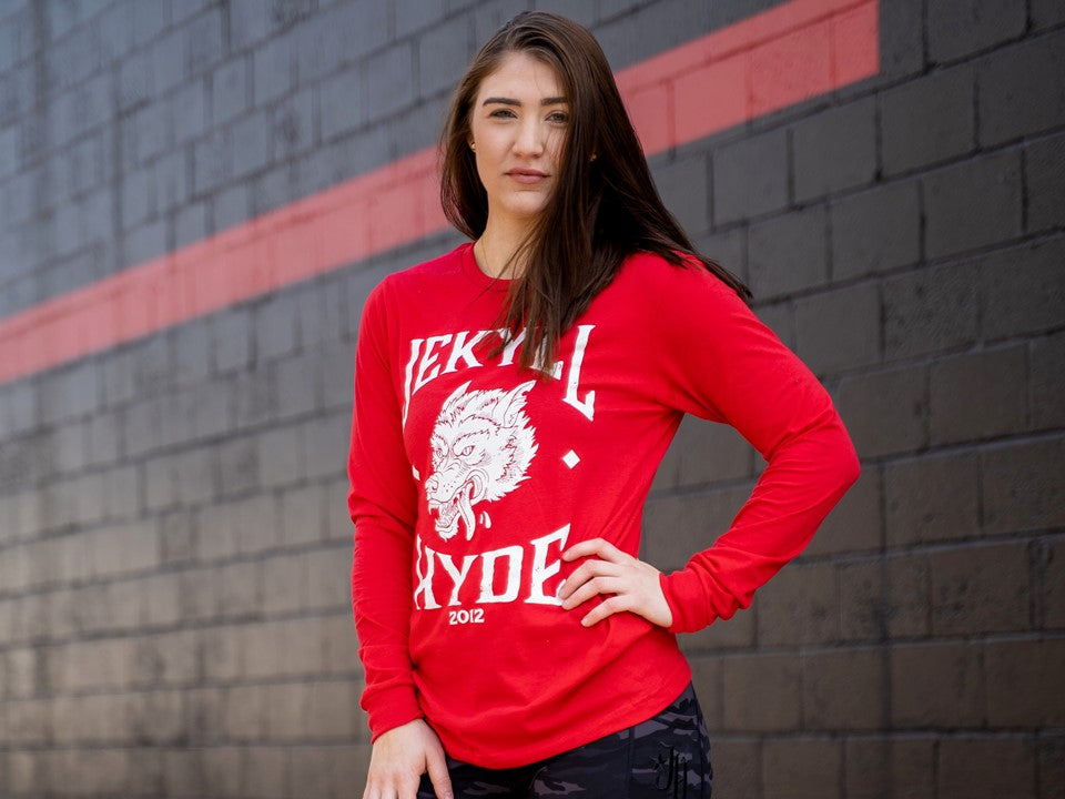 Woman standing in red long sleeve shirt with a wolf on front. 