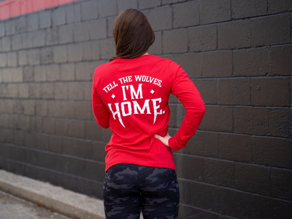 Woman in red shirt with the words "Tell the Wolves I'm Home."
