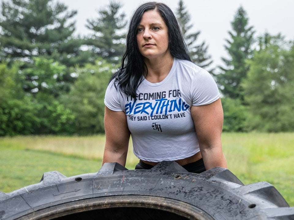 Woman flipping a tire in a white crop top. 