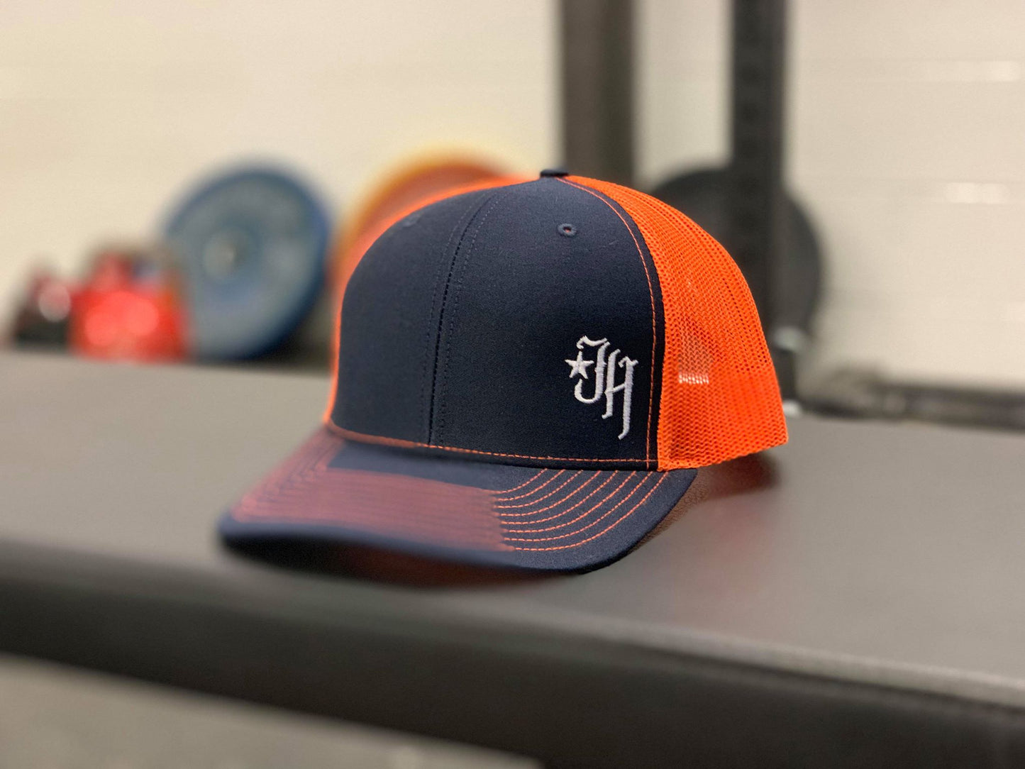 Navy and Orange trucker hat on a bench. 