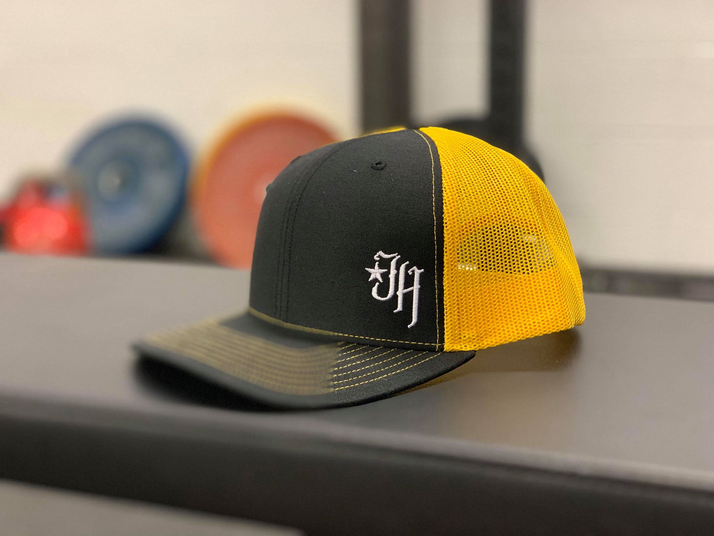 Black and gold trucker hat on a bench. 