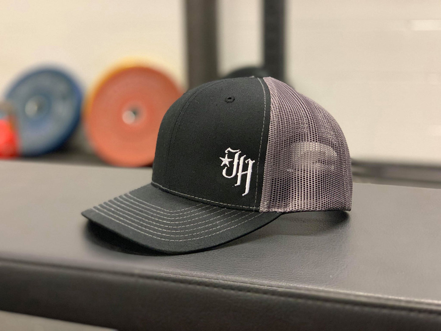 Black and Grey trucker hat on a bench. 