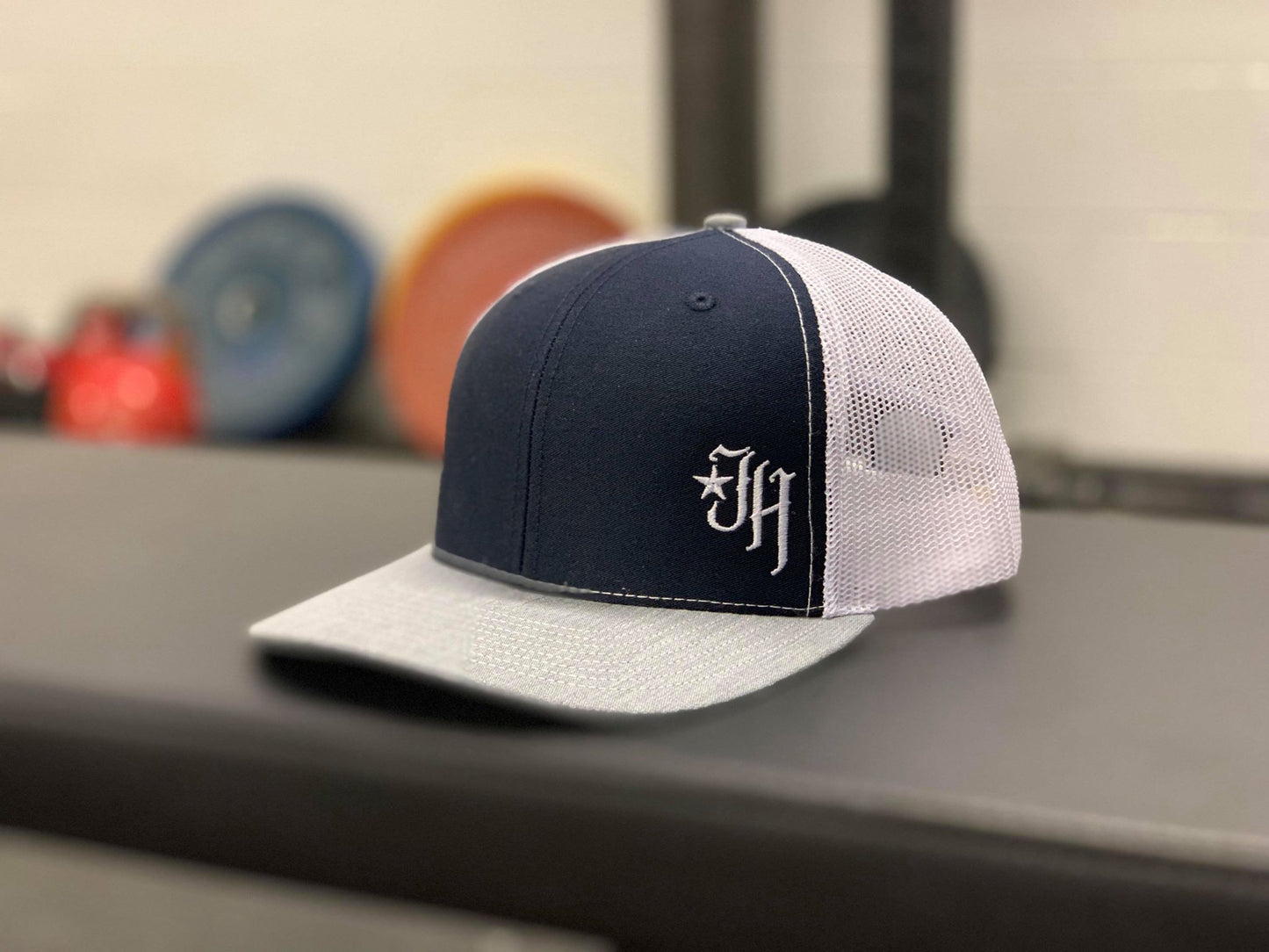 Navy, white and grey trucker hat on a bench. 