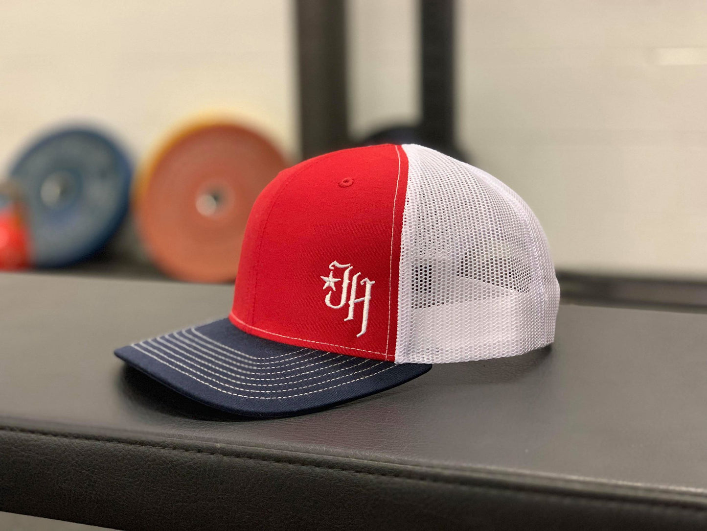Red, white a blue trucker hat on a bench. 