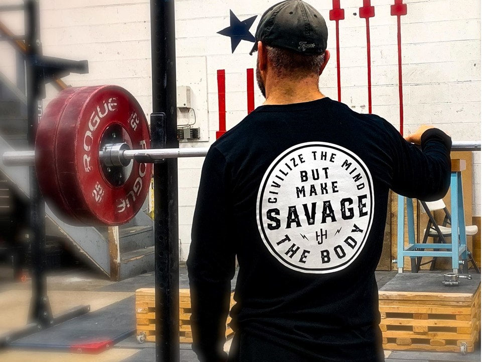 Man standing at a squat rack in black long sleeve. 