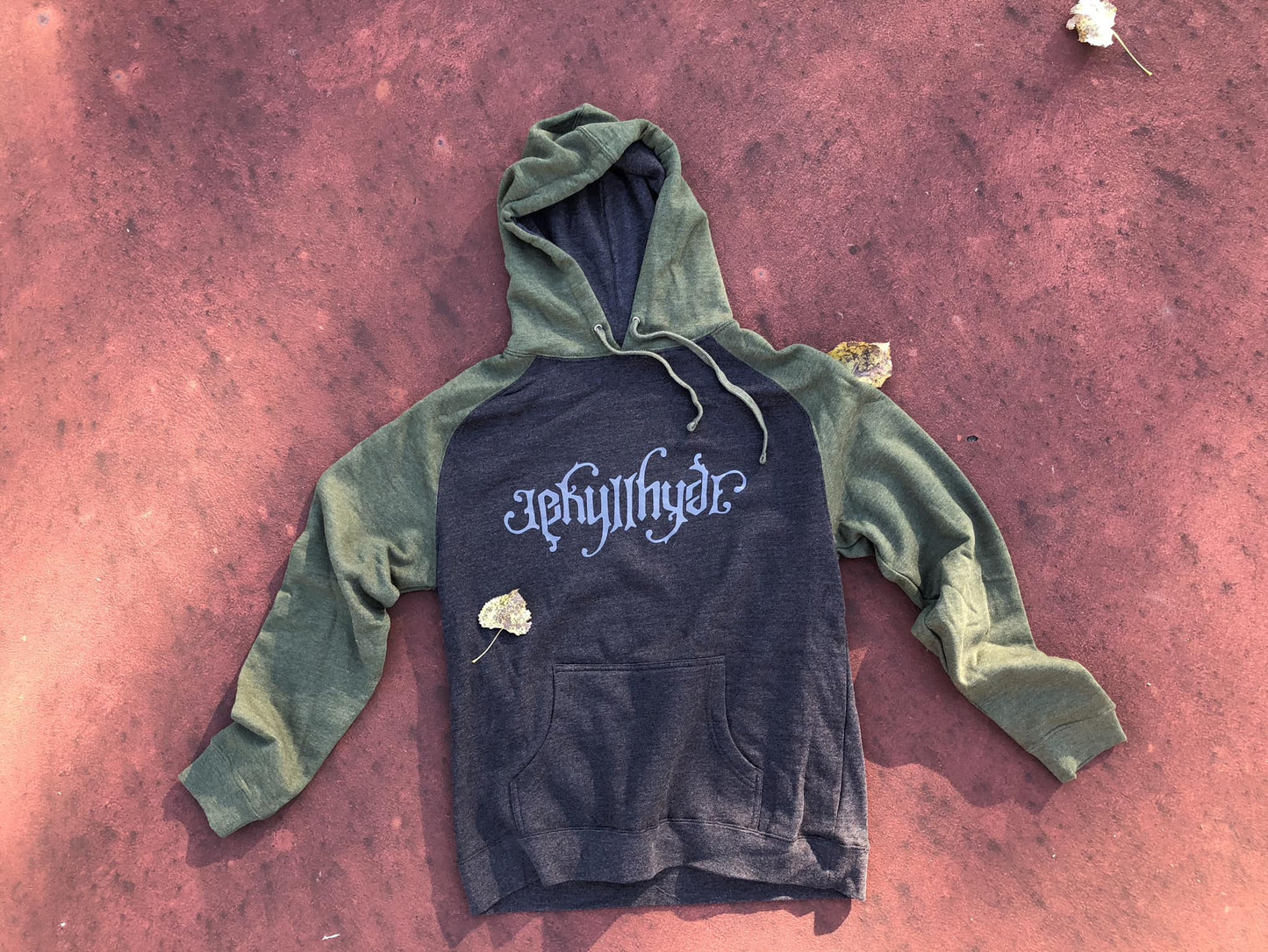 Green and charcoal hoodie on a reddish floor. 