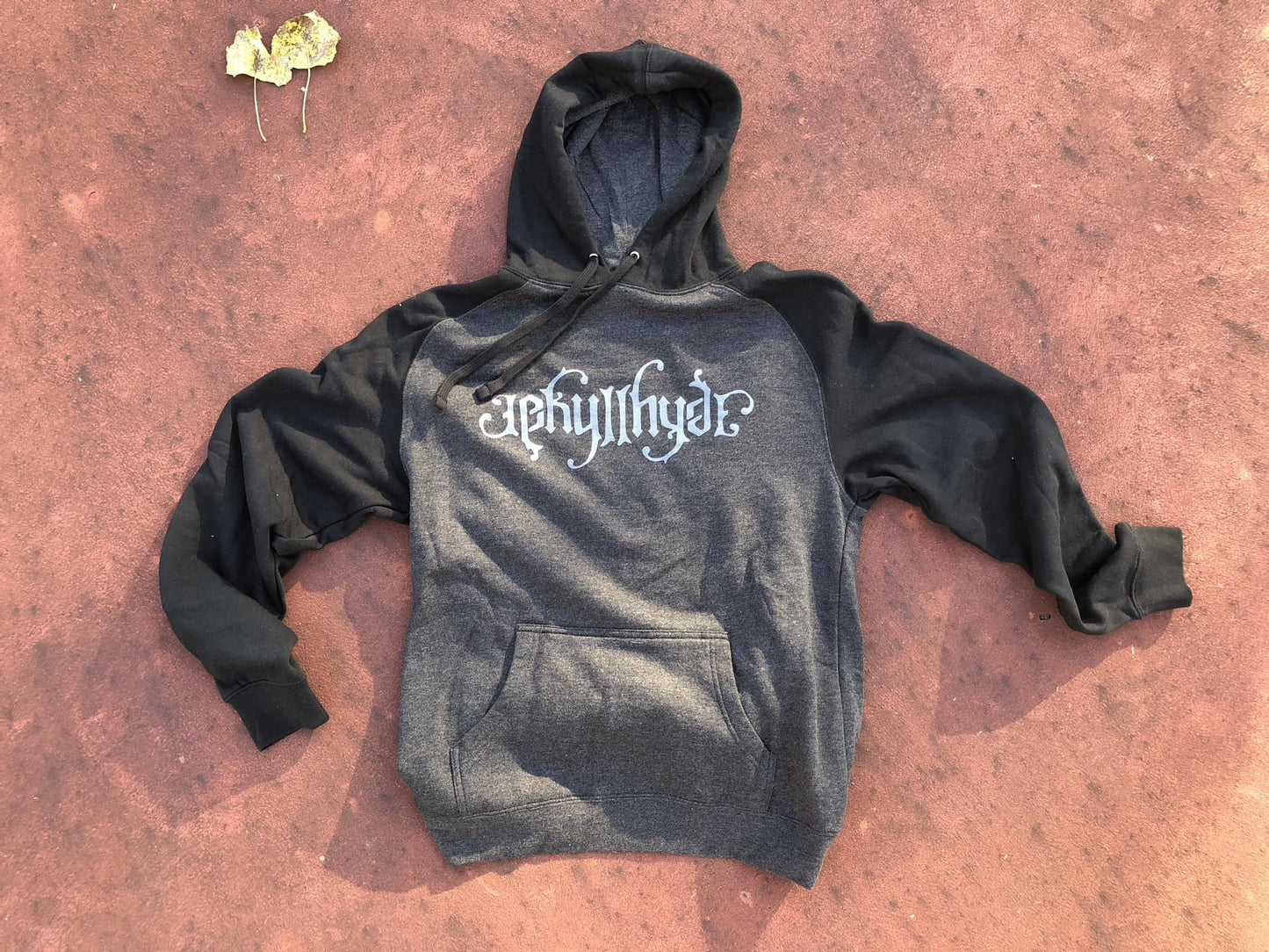 Black and charcoal hoodie on a reddish floor. 
