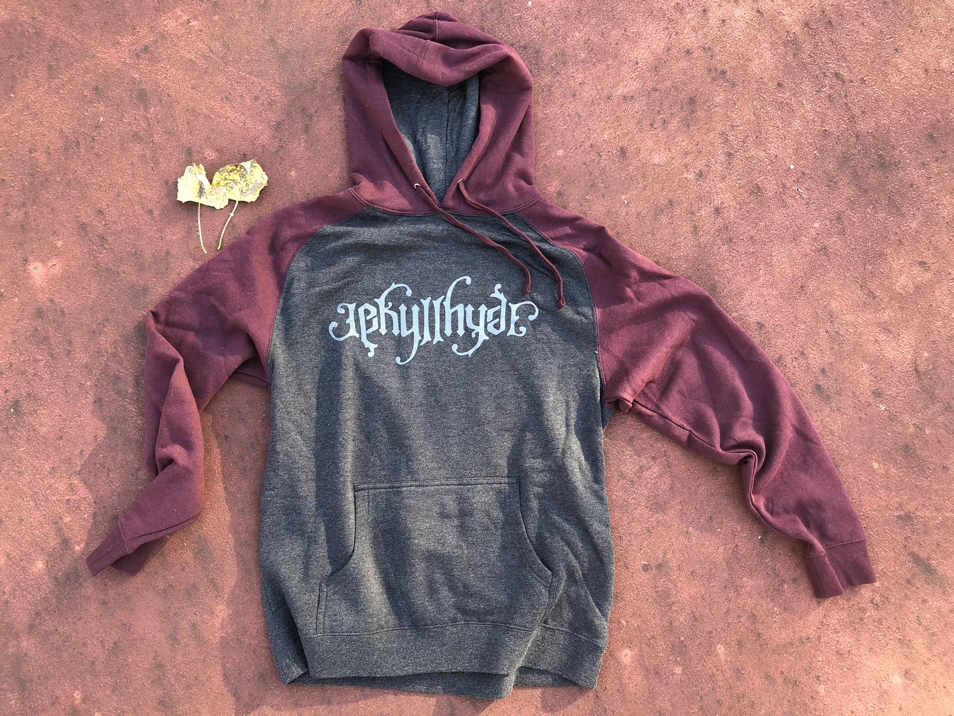 Maroon and charcoal hoodie on a reddish floor. 