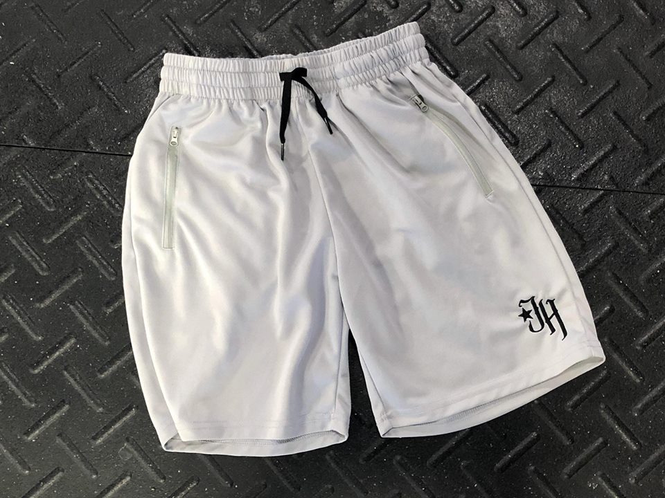 Light grey shorts flat laid on a black textured surface. 