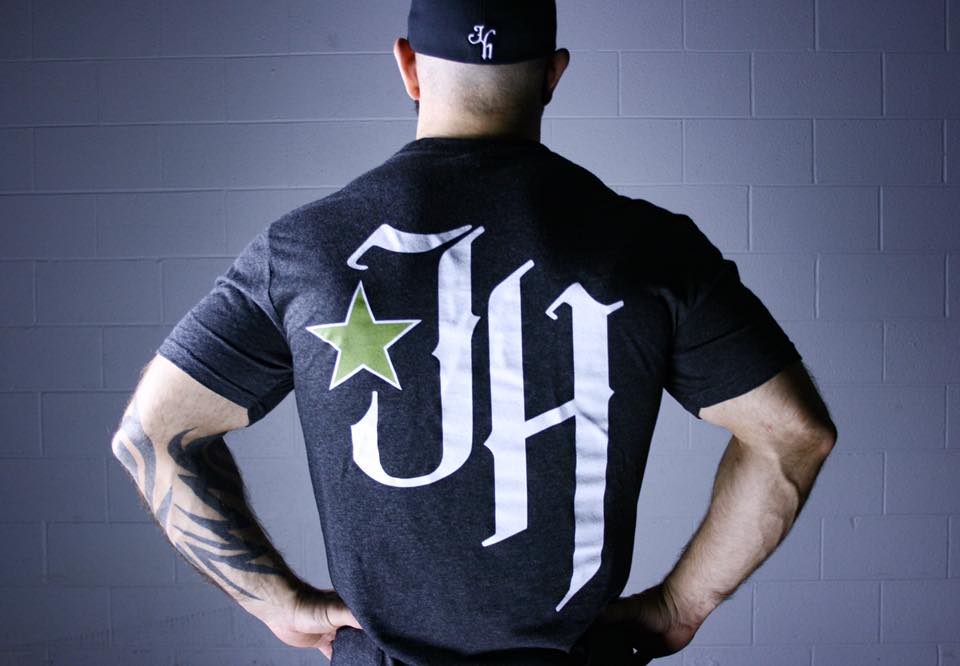 Man standing with his back to the camera against a white cinderblock wall background. 
