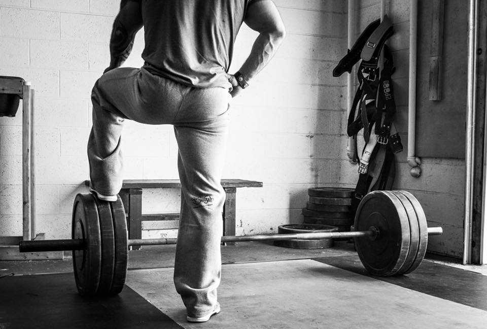 Man standing at a barbell with one foot on the weights. 